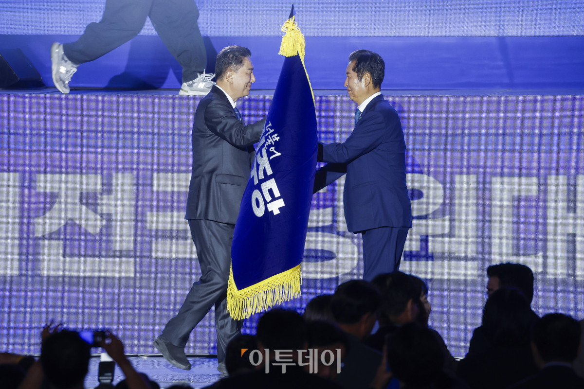 ▲정청래(오른쪽) 더불어민주당 신임 당대표가 2일 경기 고양시 킨텍스에서 열린 제2차 임시전국당원대회에서 김병기 원내대표에게 당기를 이양받고 있다. 조현호 기자 hyunho@