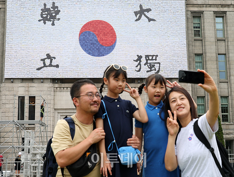 ▲3일 서울 중구 서울도서관 외벽 대형 글판인 꿈새김판이 '광복 80주년, 서울의 기억'을 주제로 새롭게 단장한 가운데 한 가족이 글판을 배경으로 기념촬영을 하고 있다. 꿈새김판은 안중근 의사의 혈서 태극기를 바탕으로 서울 독립유공자 사진 150여점, 서울기록원이 보유하고 있는 광복 당시의 사진과 이후 서울 주요 장소 사진 등 총 4000여 장의 사진을 활용해 포토모자이크로 만들었다. 고이란 기자 photoeran@