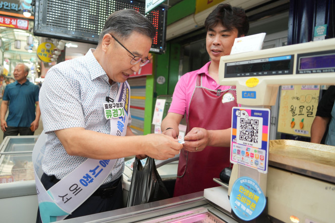 ▲류경기(왼쪽) 중랑구청장이 5일 동원시장을 찾아 물건을 구입하고 있다.  (사진제공=중랑구)