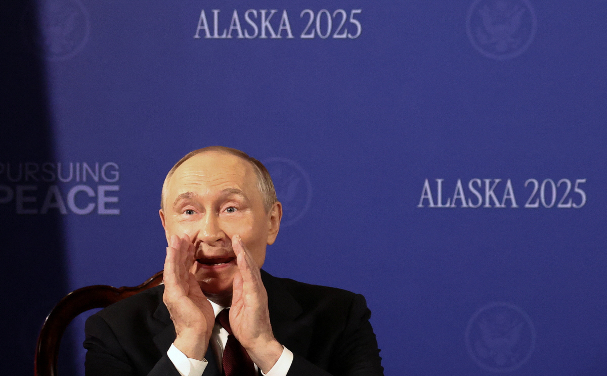 ▲블라디미르 푸틴 러시아 대통령이 15일(현지시간) 도널드 트럼프 미국 대통령과 대화하던 중 주변에 무언가를 전달하고 있다.  (앵커리지/로이터연합뉴스)