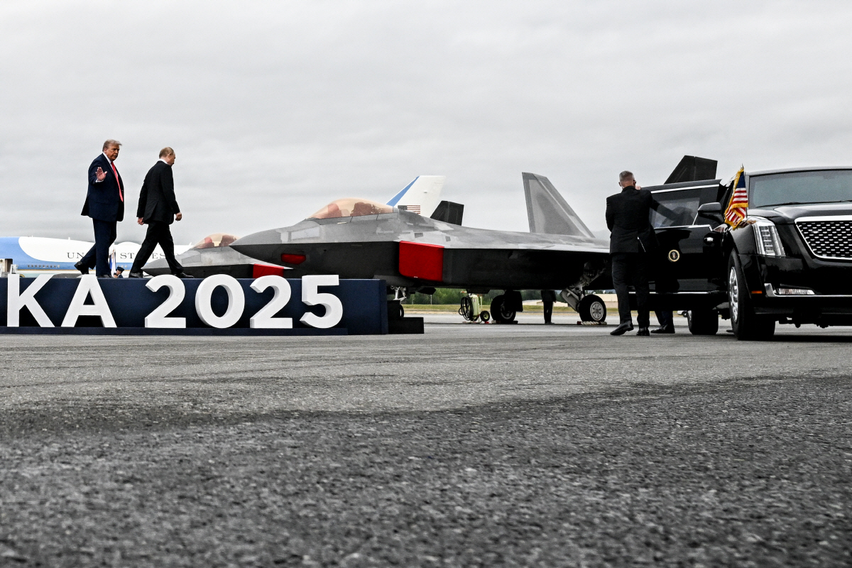 ▲15일(현지시간) 리무진으로 향하는 도널드 트럼프(왼쪽) 미국 대통령과 블라디미르 푸틴 러시아 대통령 너머로 미군 F-22 전투기가 보인다.  (앵커리지/타스연합뉴스)