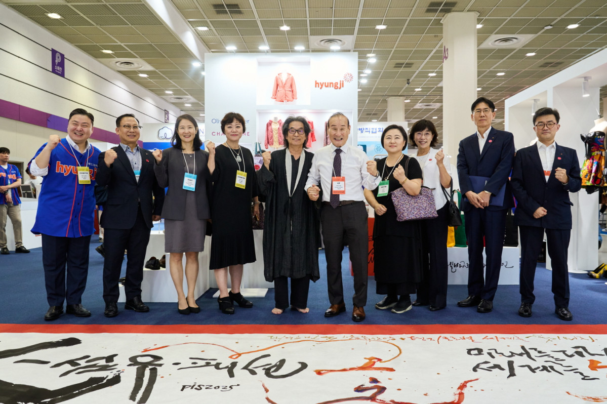 ▲'프리뷰 인 서울 2025' 패션그룹형지관 앞에서 최병오 패션그룹형지 회장(오른쪽 다섯번째)와 최준호 패션그룹형지 부회장(왼쪽 첫번째)와 붓글씨 퍼포먼스를 펼친 강병인 작가(왼쪽 다섯번째)가 기념사진을 촬영하고 있다. (사진제공=패션그룹형지)