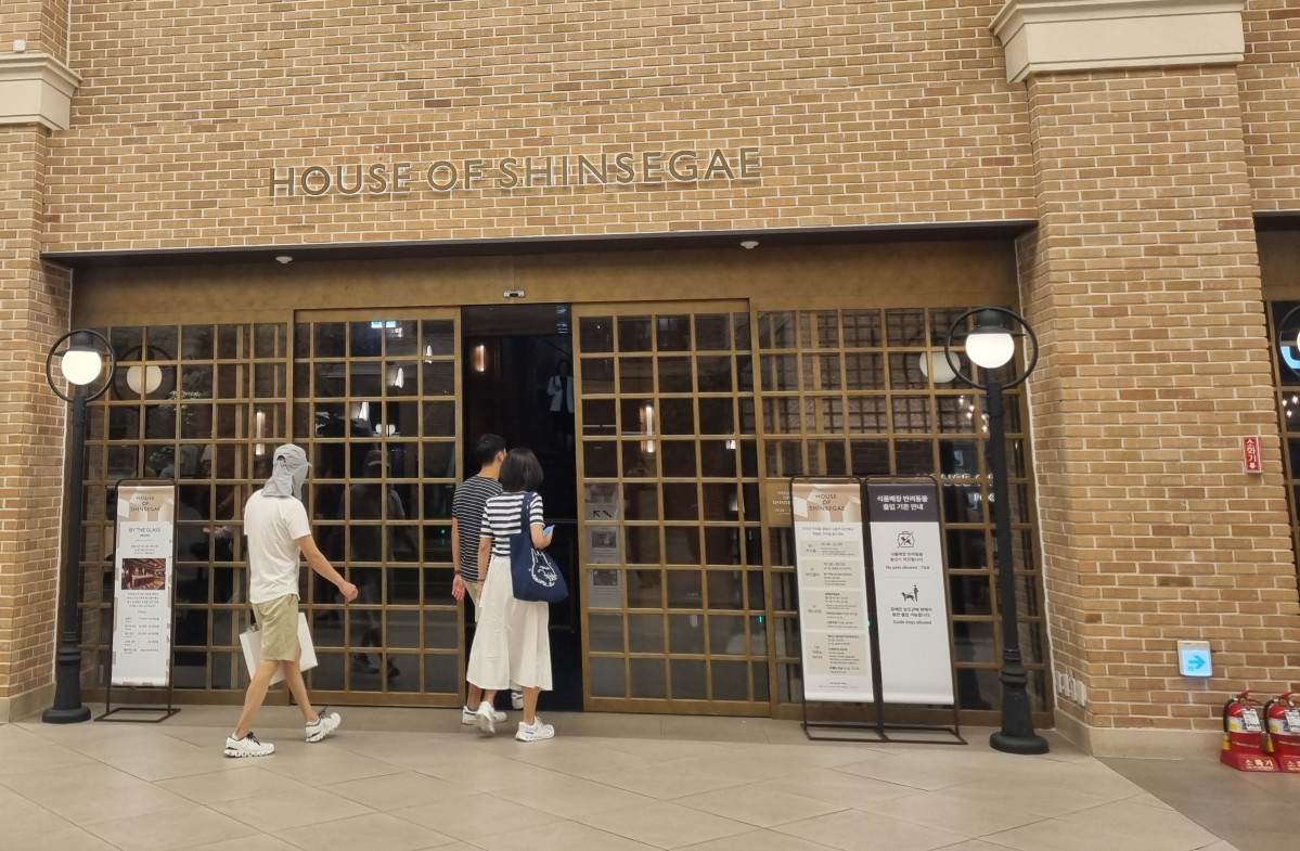 ▲8월 19일 오후 8시30분께 고객들이 ‘하우스오브신세계’로 들어가고 있다. 해당 공간의 조도가 낮아 어둠 속으로 들어가는 느낌이 들기도 한다. 입구에는 ‘미식과 주류를 곁들인 고품격 공간에서 특별한 추억을 쌓으세요’라고 적혀 있다. (유하영 기자 haha@)