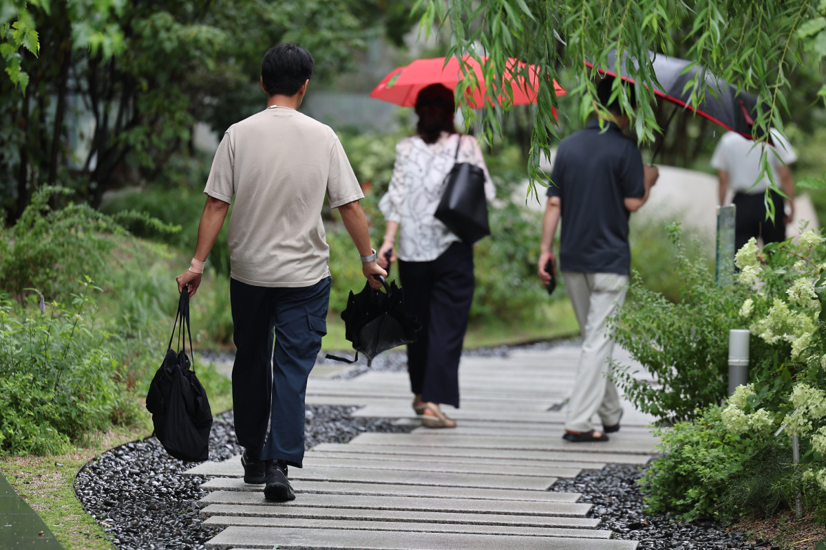 ▲아침까지 호우가 이어지다 잦아든 14일 서울 종로구 광화문광장 인근에서 한 시민이 비가 잦아들자 우산을 접고 이동하고 있다. (사진제공=연합뉴스)