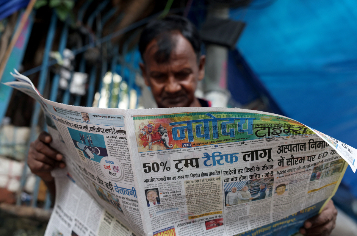 ▲인도 뉴델리에서 27일(현지시간) 한 시민이 미국의 자국에 대한 50% 관세가 발효했다는 소식이 실려 있는 신문을 읽고 있다. 뉴델리/로이터연합뉴스