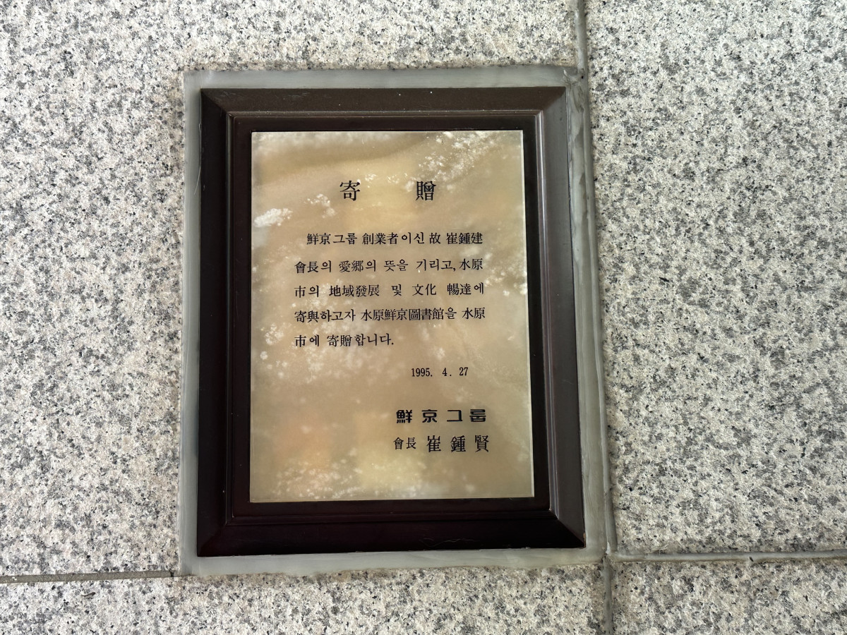 ▲수원 선경도서관 내부 동판에는 기증에 대한 내용이 담겨 있다. 1995년 4월 27일 세워졌고 선경그룹 창업자 최종건 회장의 애향 정신을 기리며 최종현 회장이 선경도서관을 수원시에 기증한다는 내용이다.  (이수진 기자)