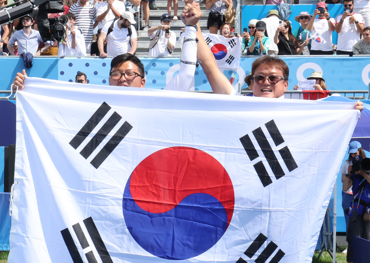 ▲지난해 8월 4일(현지시간) 프랑스 파리 레쟁발리드에서 열린 2024 파리올림픽 양궁 남자 개인전 미국의 브레이디 엘리슨과의 결승에서 승리한 한국 김우진이 박성수(오른쪽) 감독과 태극기를 들고 관중에게 인사하고 있다. (연합뉴스)