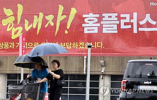 ▲홈플러스 매각 본입찰 무산 소식이 전해진 26일, 서울에서 흐린 날씨 속 시민들이 '힘내자! 홈플러스'라고 적힌 현수막 앞을 우산을 쓰고 지나가고 있다. (연합뉴스)