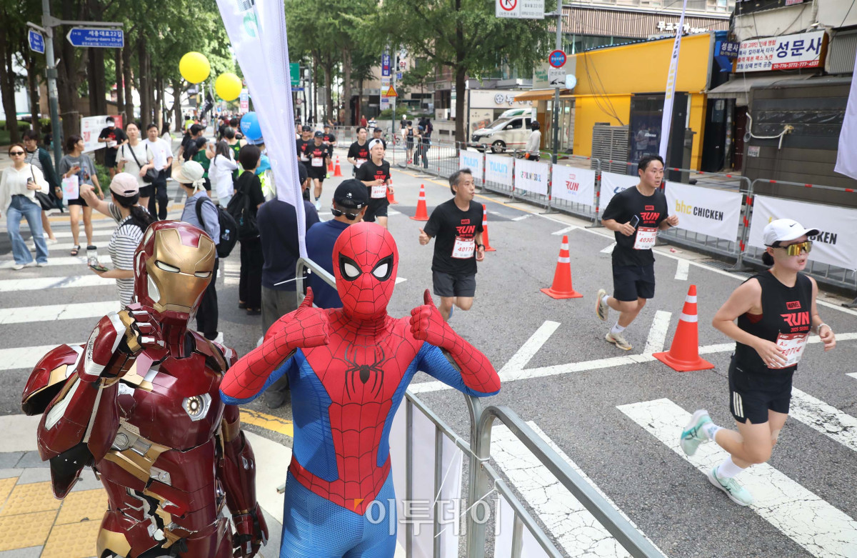 ▲14일 오전 서울광장에서 열린 ‘마블런 서울 2025’ 행사에서 마블 히어로 코스튬을 입은 팬이 러너들을 응원하고 있다. 사진제공=디즈니