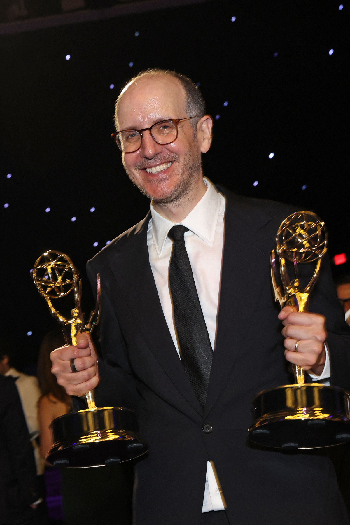 ▲에미상에서 두 개의 트로피를 들고 있는 사람이 어두운 배경과 별빛 아래 시상식의 환희를 보여주고 있다. (연합뉴스)