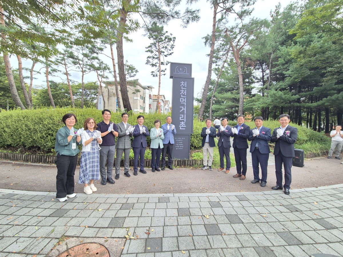 ▲박옥분 경기도의원, 오세철·조문경 수원특례시의회 의원 등 참석자들이 천천먹거리촌 기념 표지판 옆에서 점포환경개선사업 성과 기념행사에 참여하고 있다. (수원도시재단)