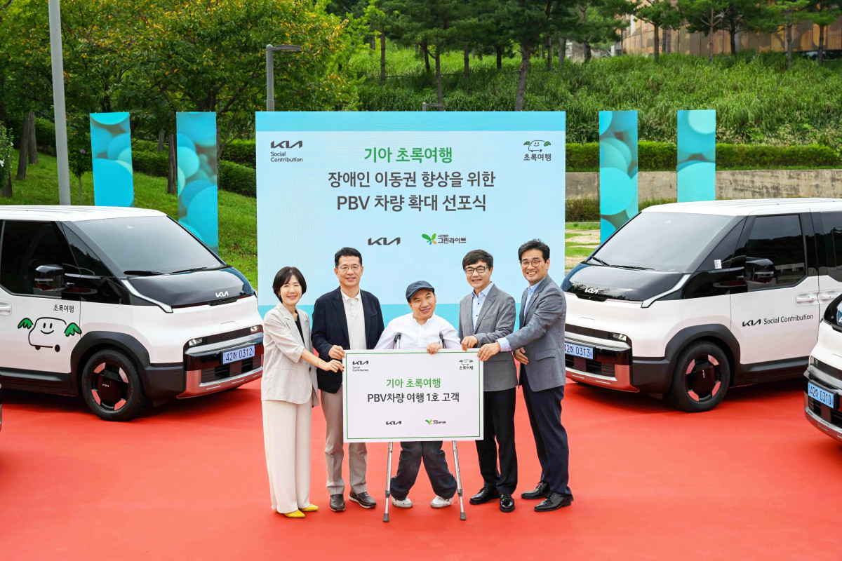 ▲기아 지속가능경영실장 이덕현 상무(왼쪽 두 번째), 사단법인 그린라이트 이재강 회장(왼쪽 네 번째) 등 주요 관계자들이 PV5 여행 1호 고객과 기념 촬영을 하고 있는 모습. (사진=기아)