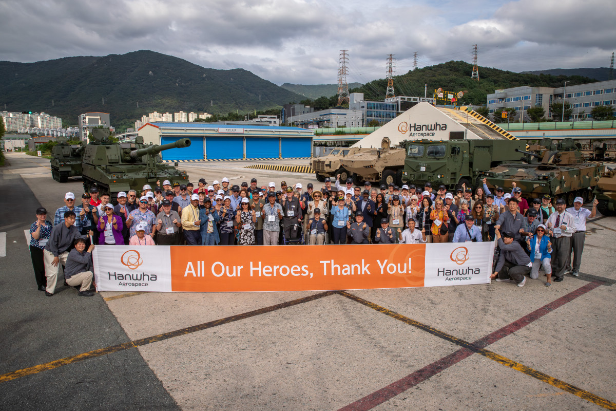 ▲지난 19일 한화에어로스페이스 창원2사업장에서 진행된 '참전용사 재방한 행사'에서 6·25전쟁 미국 참전용사 85명 등 관계자들이 주요 무기체계 앞에서 기념촬영하고 있다. (한화에어로스페이스)