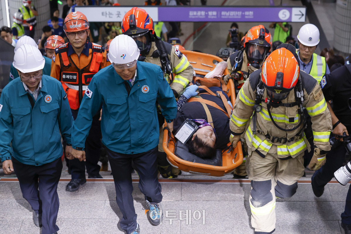 ▲오세훈 서울시장이 22일 서울 영등포구 여의나루역 일대에서 열린 2025년 서울시 재난대응 안전한국훈련에서 소방대원들과 함께 인명 구조 훈련을 하고 있다. 재난대응 안전한국훈련은 지하 47m(아파트 16층 높이)에 위치해 지상으로 이동 동선이 긴 5호선 여의나루역에서 휴대용 배터리 발화 및 고의적 방화로 화재가 발생, 대피 중 인파 사고와 흉기 난동 등이 복합적으로 발생하는 상황을 가정해 이뤄졌다. 조현호 기자 hyunho@