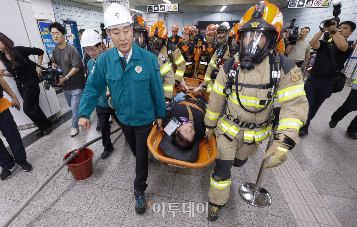 ▲오세훈 서울시장이 22일 서울 영등포구 여의나루역 일대에서 열린 2025년 서울시 재난대응 안전한국훈련에서 소방대원들과 함께 인명 구조 훈련을 하고 있다. 재난대응 안전한국훈련은 지하 47m(아파트 16층 높이)에 위치해 지상으로 이동 동선이 긴 5호선 여의나루역에서 휴대용 배터리 발화 및 고의적 방화로 화재가 발생, 대피 중 인파 사고와 흉기 난동 등이 복합적으로 발생하는 상황을 가정해 이뤄졌다. 조현호 기자 hyunho@