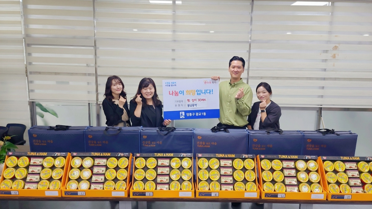 ▲이경수 동남용역 대표와 송숙영 광교1동장이 참치와 햄 세트 30박스 앞에서 기념사진을 찍었다. (수원시 영통구 광교1동)