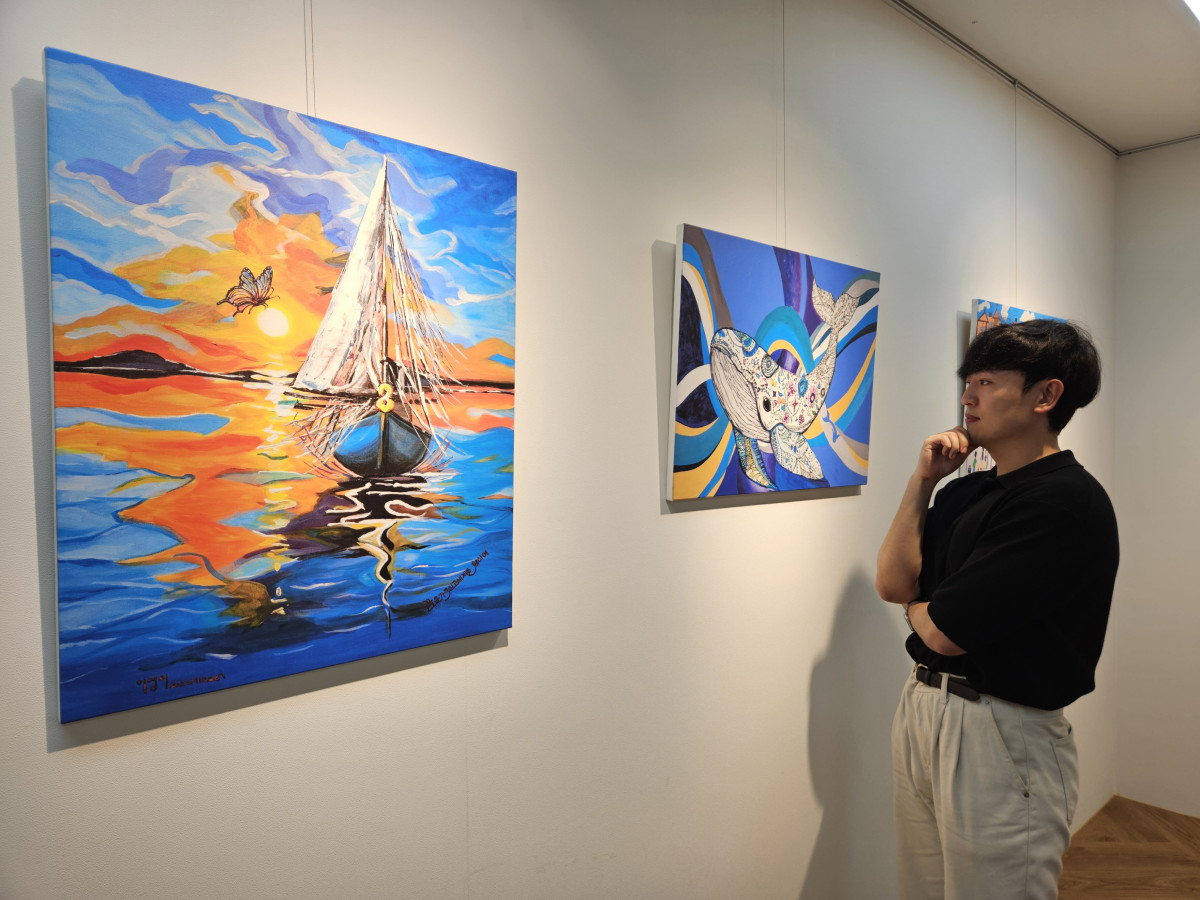 ▲현대제철 직원이 ㈜올모용인 사업장에 걸린 소속 발달장애인 작가들의 작품을 감상하고 있다 (사진= 현대제철)