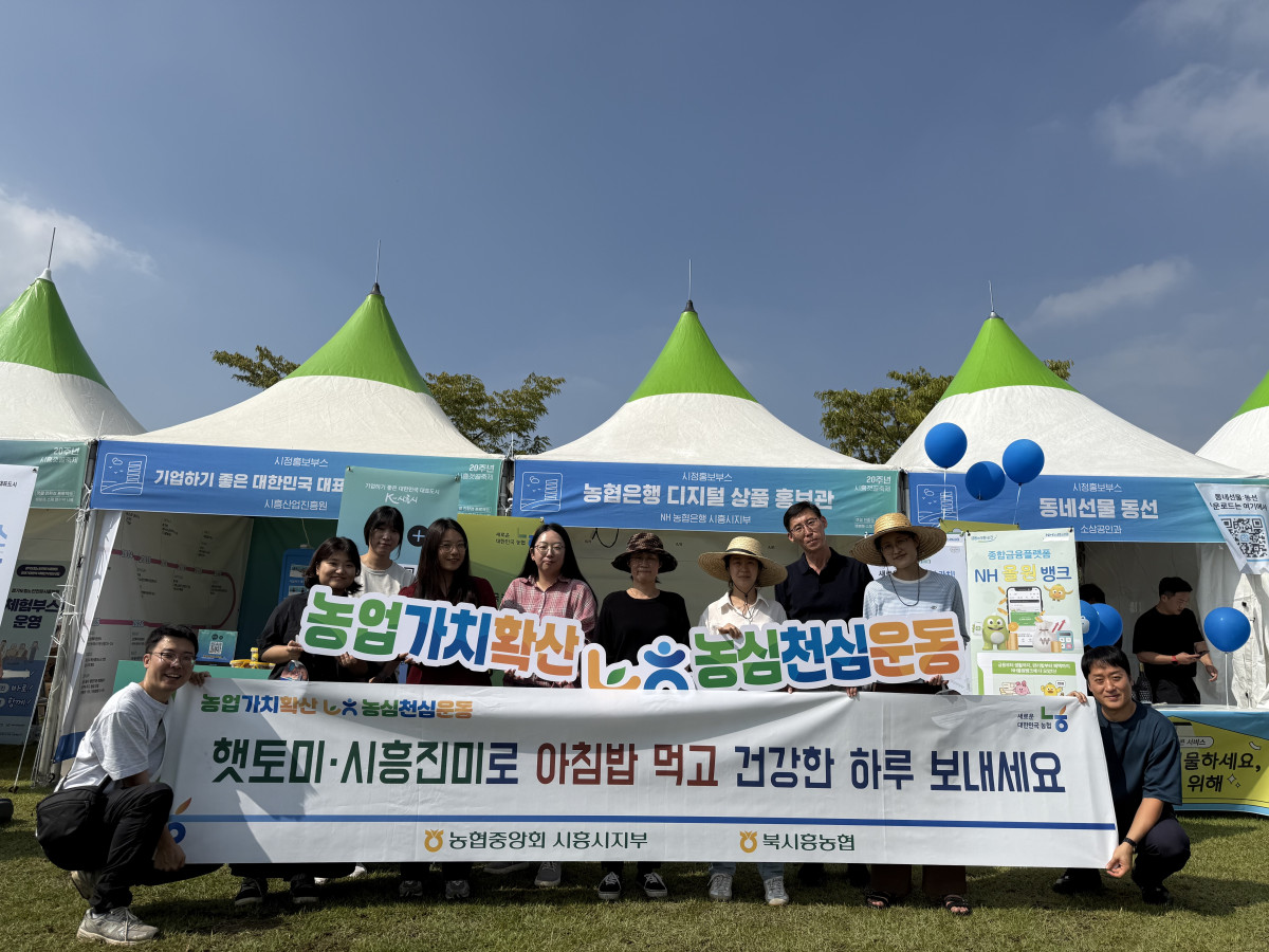 ▲NH농협 시흥시지부 임직원과 농업기술센터 관계자들이 갯골축제 현장에서 농심천심운동 캠페인 홍보 현수막을 들고 단체사진을 찍고 있다. (경기농협)