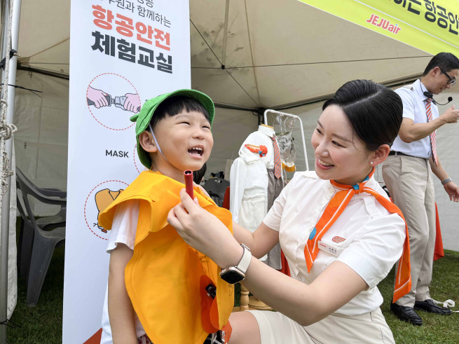 ▲제주항공 객실승무원들이 26일 제주시 시민복지타운에서 진행된 '제17회 제주 범도민 안전체험 한마당'에서 어린이에게 비상상황 발생시 구명조끼 착용 방법을 가르쳐 주고 있다. (사진제공=제주항공)