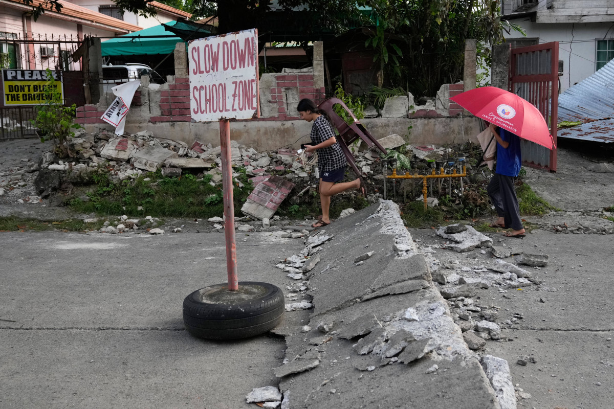 ▲2일(현지 시간) 필리핀 중부 세부주 보고에서 주민들이 지진으로 파손된 도로를 지나고 있다. (AP/뉴시스)