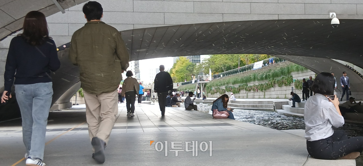 ▲15일 오후 시민들과 외국인들이 서울 종로구 모전교 밑에서 청계천을 따라 걷거나 바닥에 앉아 더위를 피하는 모습이다. 황수민 수습기자 breathein@