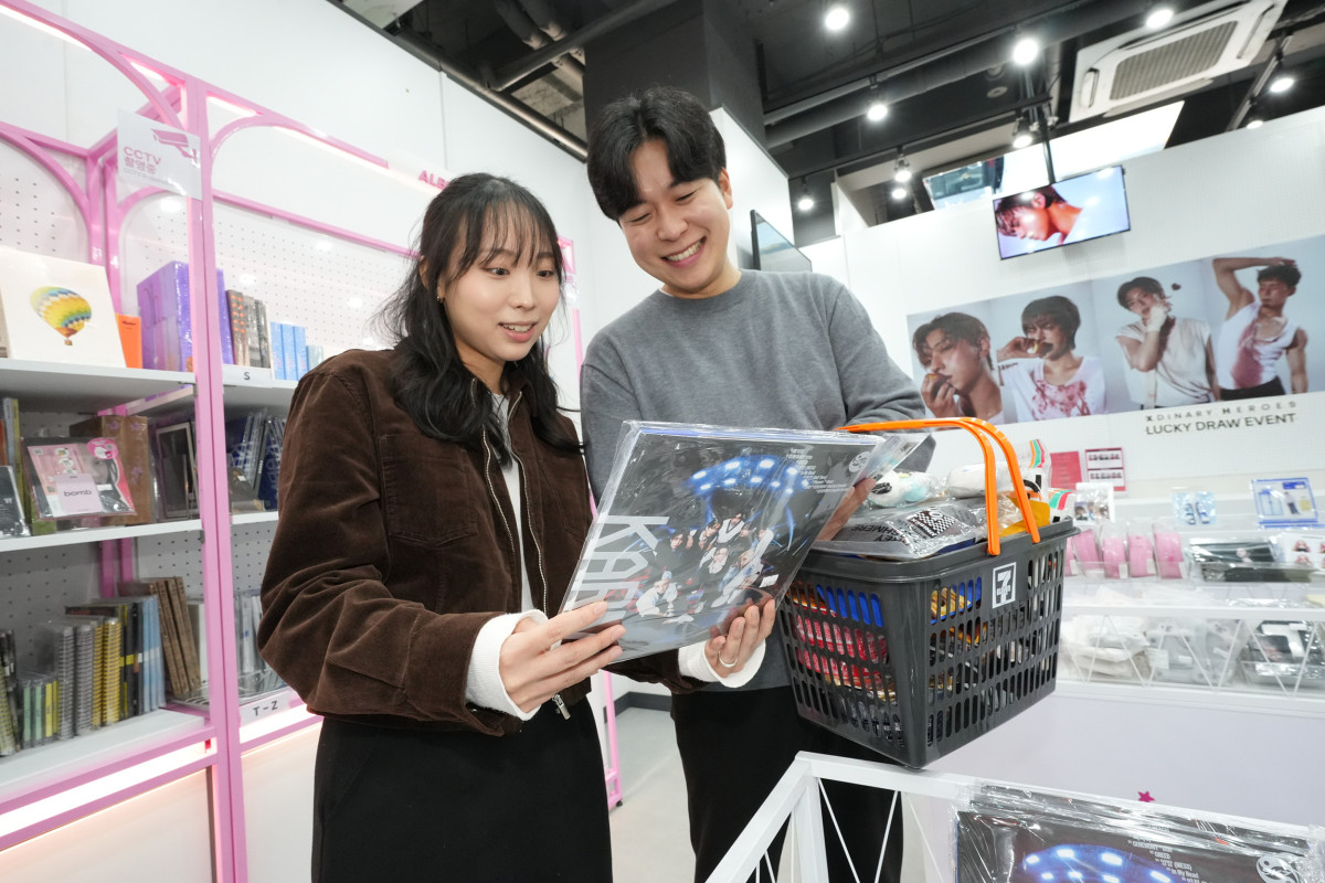 ▲세븐일레븐 뉴웨이브 명동점 내 후즈팬 스토어에서 모델들이 케이팝 앨범을 구경하고 있다.  (사진제공=세븐일레븐)