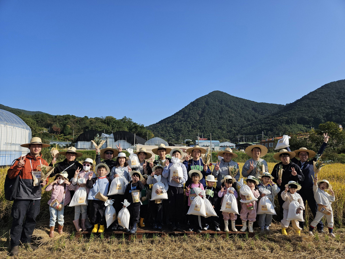 ▲거제 30인의 아빠단이 자녀들과 벼베기를 마치고 기념촬영을 하고 있다.  (사진제공=거제시)
