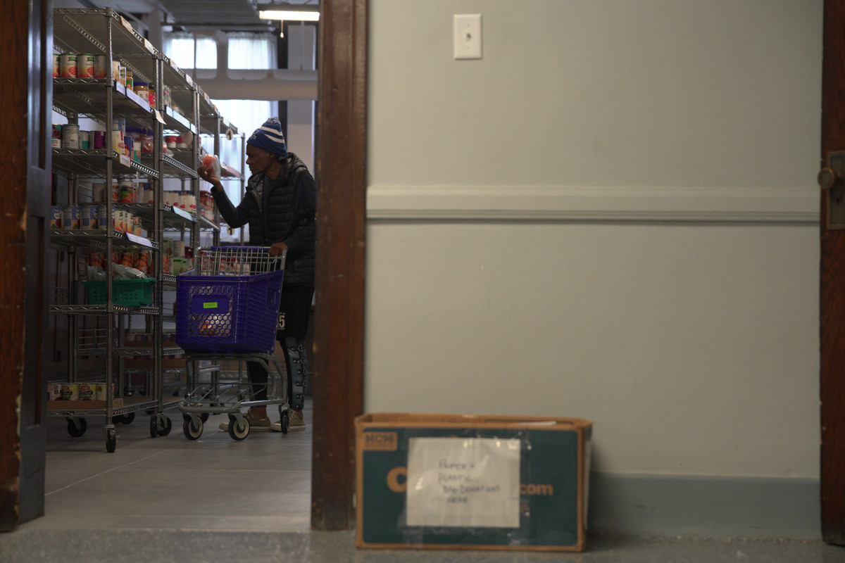 ▲25일(현지시간) 미 인디애나폴리스에 있는 센트럴크리스천 교회 내 푸드뱅크의 선반에 있는 식표룸을 한 여성이 바라보고 있다. (AP연합뉴스)