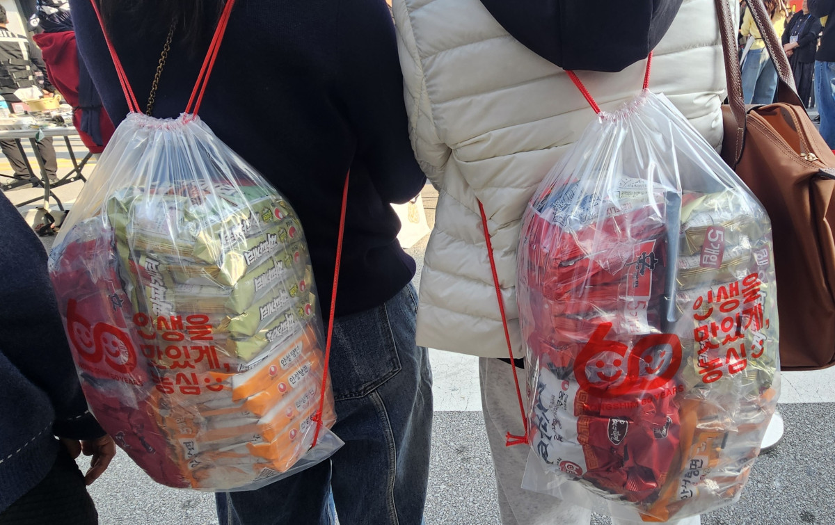 ▲7일 경상북도 구미시에서 열린 ‘2025 구미라면축제’에서 판매된 갓 튀긴 라면 5종 패키지 가방을 방문객들이 메고 있다. (사진=정영인 기자 oin@)