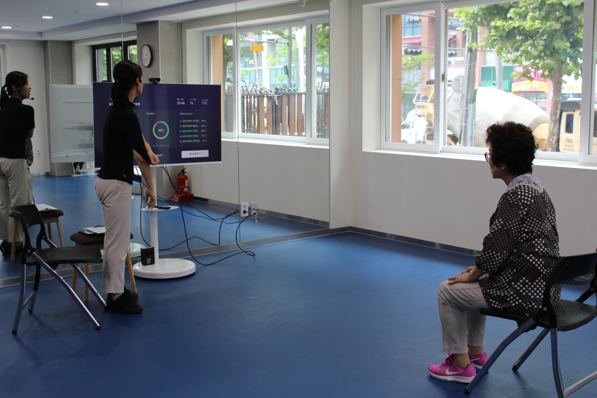 ▲강남종합사회복지관 운동지도사가 AI 운동기기 ‘엑서사이트케어’를 활용해 어르신에게 맞춤운동을 지도하고 있다.(강남종합사회복지관 제공)