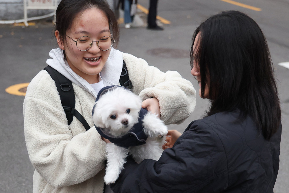 ▲2026학년도 대학수학능력시험(수능)이 치러진 13일 서울 중구 이화여자외국어고등학교에서 한 가족이 강아지와 수험생을 응원하고 있다.  (연합뉴스)