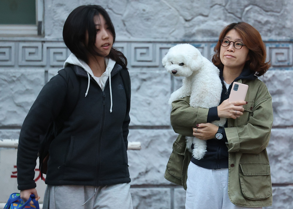 ▲2026학년도 대학수학능력시험(수능)이 치러진 13일 서울 중구 이화여자외국어고등학교 앞에서 한 학부모가 반려견을 안고 수험생을 지켜보고 있다.  (연합뉴스)