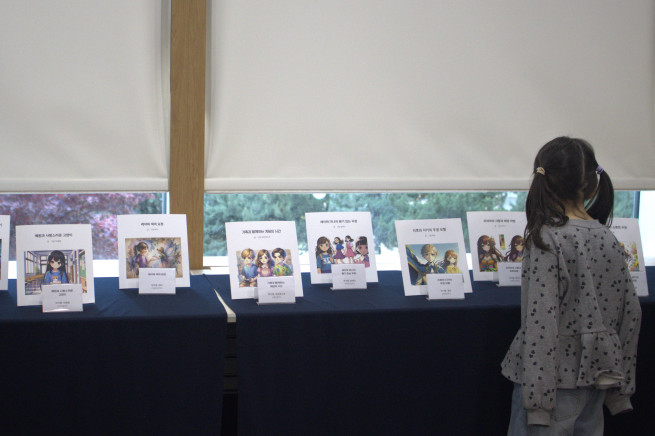 ▲18일 서울 용산구 삼일미래재단 본사에서 초등학생들이 제작한 '나만의 AI 동화책'이 전시된 가운데, 한 참가자가 작품들을 둘러보고 있다. (제공=삼일PwC)