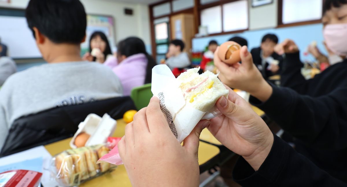 ▲학교 비정규직 노동자들이 파업에 돌입한 20일 인천 한 초등학교 교실에서 학생들이 구운 달걀, 주스, 햄치즈샌드위치 등 대체 급식으로 점심을 먹고 있다. (연합뉴스)