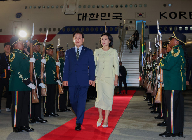 ▲주요 20개국(G20) 정상회의에 참석하는 이재명 대통령이 김혜경 여사와 함께 21일(현지시간) 남아프리카공화국 요하네스버그 OR탐보국제공항에 도착한 뒤 공군 1호기에서 내려 이동하고 있다.   (연합뉴스)