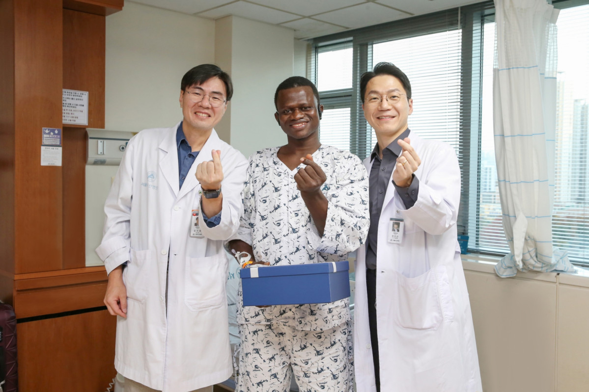 ▲서울아산병원에서 대퇴골 재건 및 피부 이식 수술을 받은 존 콘테 씨(가운데)가 13일 의료진과 기념사진을 찍고 있다. 왼쪽이 서울아산병원 김지완 정형외과 교수, 오른쪽이 권진근 성형외과 교수 (서울아산병원)