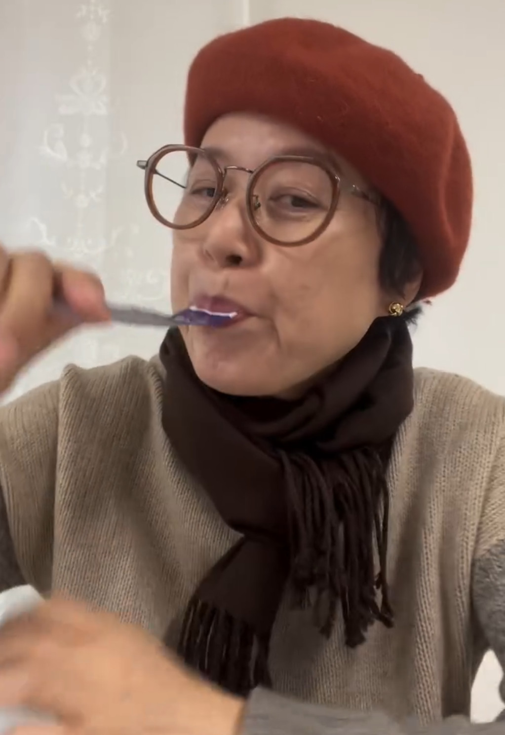 ▲공동구매 논란이 이어진 21일, 실내에서 한 사람이 붉은 베레모와 큰 안경을 착용한 채 칫솔질을 하는 모습이 포착되고 있다. (출처=박미선SNS)