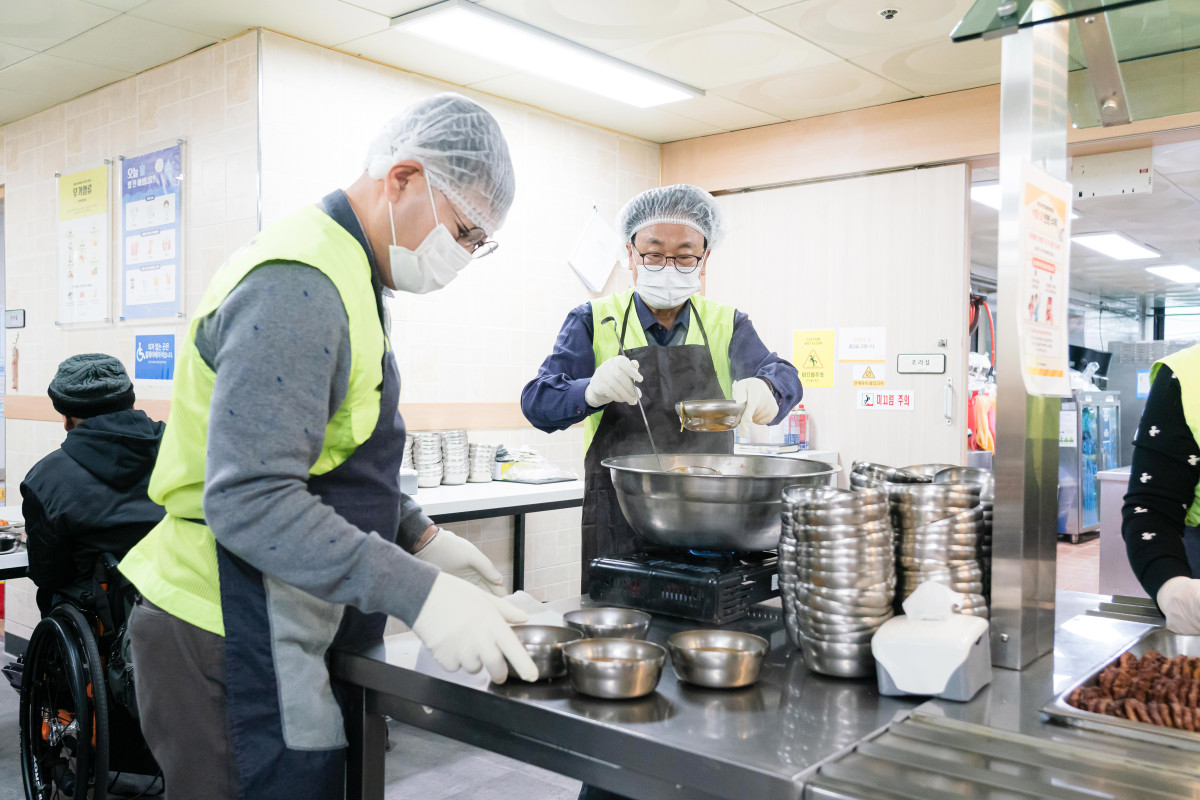 ▲말보다 손으로 전한 연말 인사. 처인장애인복지관 배식 현장에서 의원들이 이용자와 눈을 맞추며 봉사에 임하고 있다. (용인특례시의회)