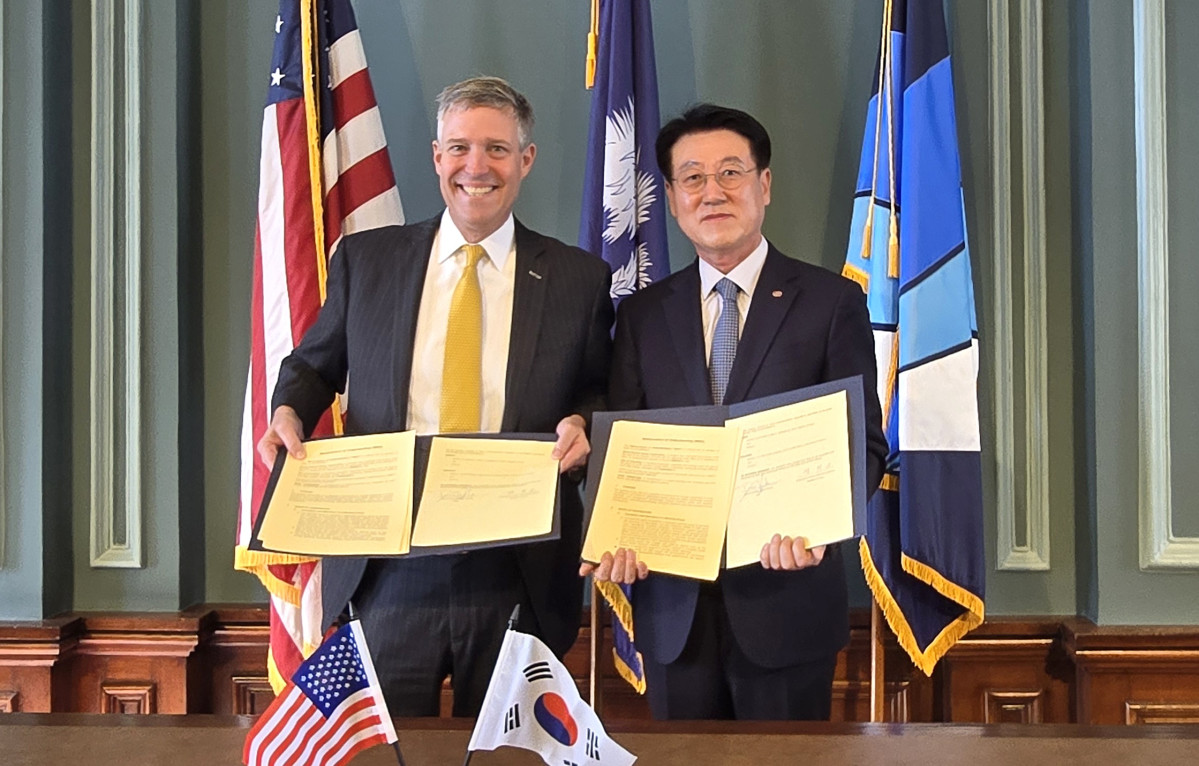 ▲13일(현지시간) 미국 사우스캐롤라이나주 컬럼비아 시의회에서 정치교 한국전력 안전영업배전부사장(오른쪽)과 대니얼 리켄만 컬럼비아시장 컬럼비아시장이 '배전망 기술협력 양해각서(MOU)'를 체결하고 기념촬영을 하고 있다. (사진제공=한국전력)