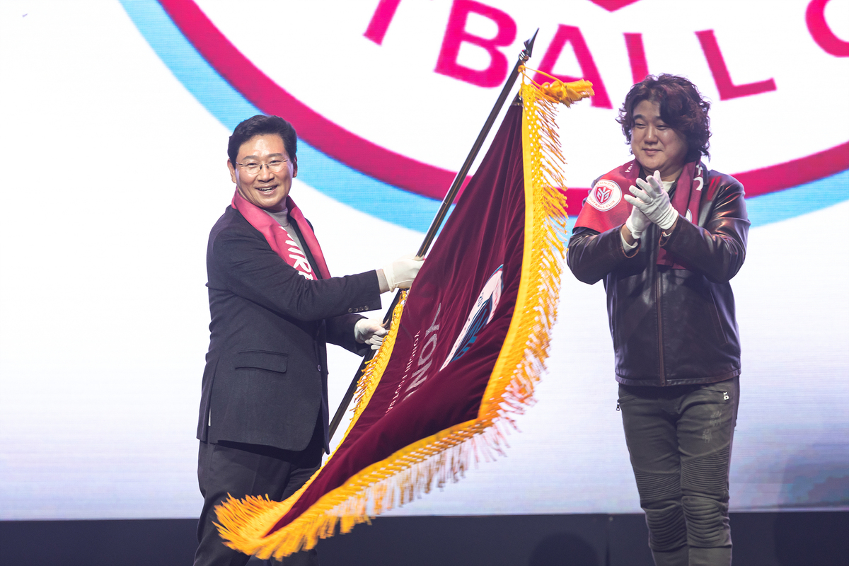 ▲상일 용인특례시장(왼쪽)이 16일 한국프로축구연맹 2026 K리그 정기 대의원 총회에서 용인FC의 K리그2 가입 승인을 받은 직후, 구단기를 들어 보이며 프로축구 원년의 역사적 순간을 자축하고 있다.  (용인특례시)