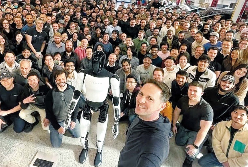 ▲자신이 개발을 주도한 휴머노이드 로봇 옵티머스를 앞에 두고 동료 직원들과 기념 촬영을 하고 있는 밀란 코박 전 부사장(맨 앞 서 있는 이). 현대차그룹은 16일 그를 자문역으로 영입했다고 밝혔다.