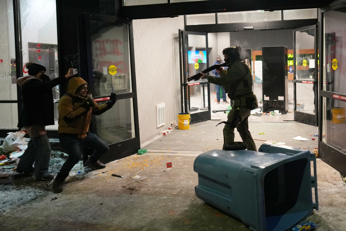 ▲미국 미네소타주 미니애폴리스에서 25일(현지시간) 한 연방요원이 호텔 밖에서 이민단속 반대 시위를 벌이는 시민을 향해 총을 겨누고 있다. (미니애폴리스(미국)/AP연합뉴스)