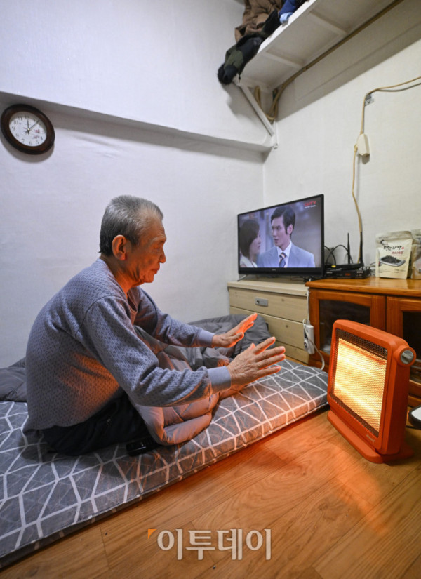 ▲영하 10도 안팎의 한파가 닷새째 이어진 23일 서울 용산구 동자동 쪽방촌에서 한 주민이 이불과 전기난로로 추위를 피하고 있다. 조현호 기자 hyunho@