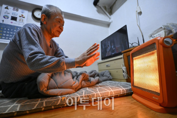 ▲영하 10도 안팎의 한파가 닷새째 이어진 23일 서울 용산구 동자동 쪽방촌에서 한 주민이 이불과 전기난로로 추위를 피하고 있다. 조현호 기자 hyunho@
