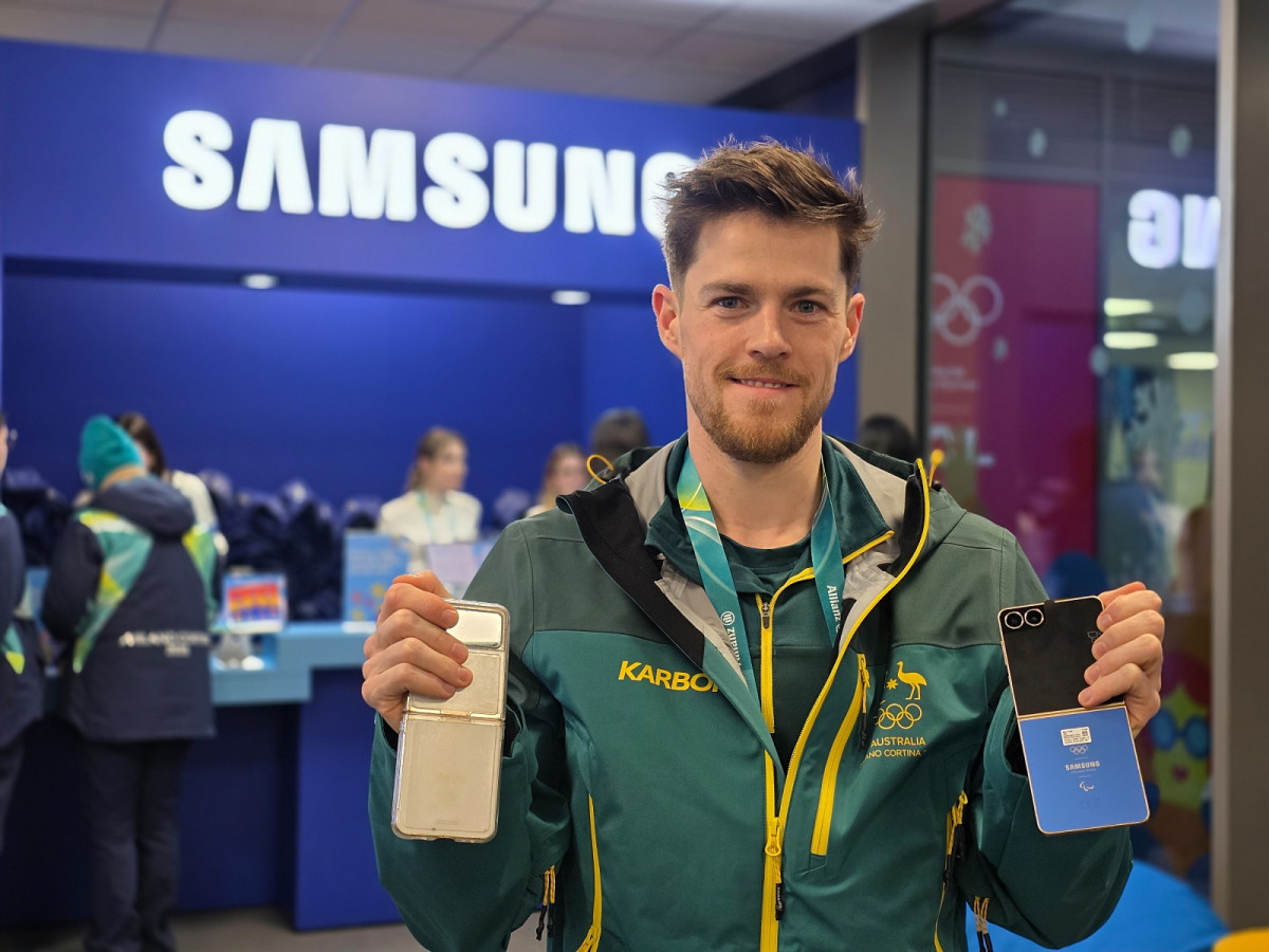 ▲브렌던 코리(호주, 스피드 스케이팅) 선수가 밀라노 올림픽 선수촌 내 삼성 체험관에 방문해 갤럭시 Z 플립7 올림픽 에디션과 지난 베이징 동계올림픽 갤럭시 Z 플립3 올림픽 에디션을 함께 보여주고 있다. (사진=삼성전자)