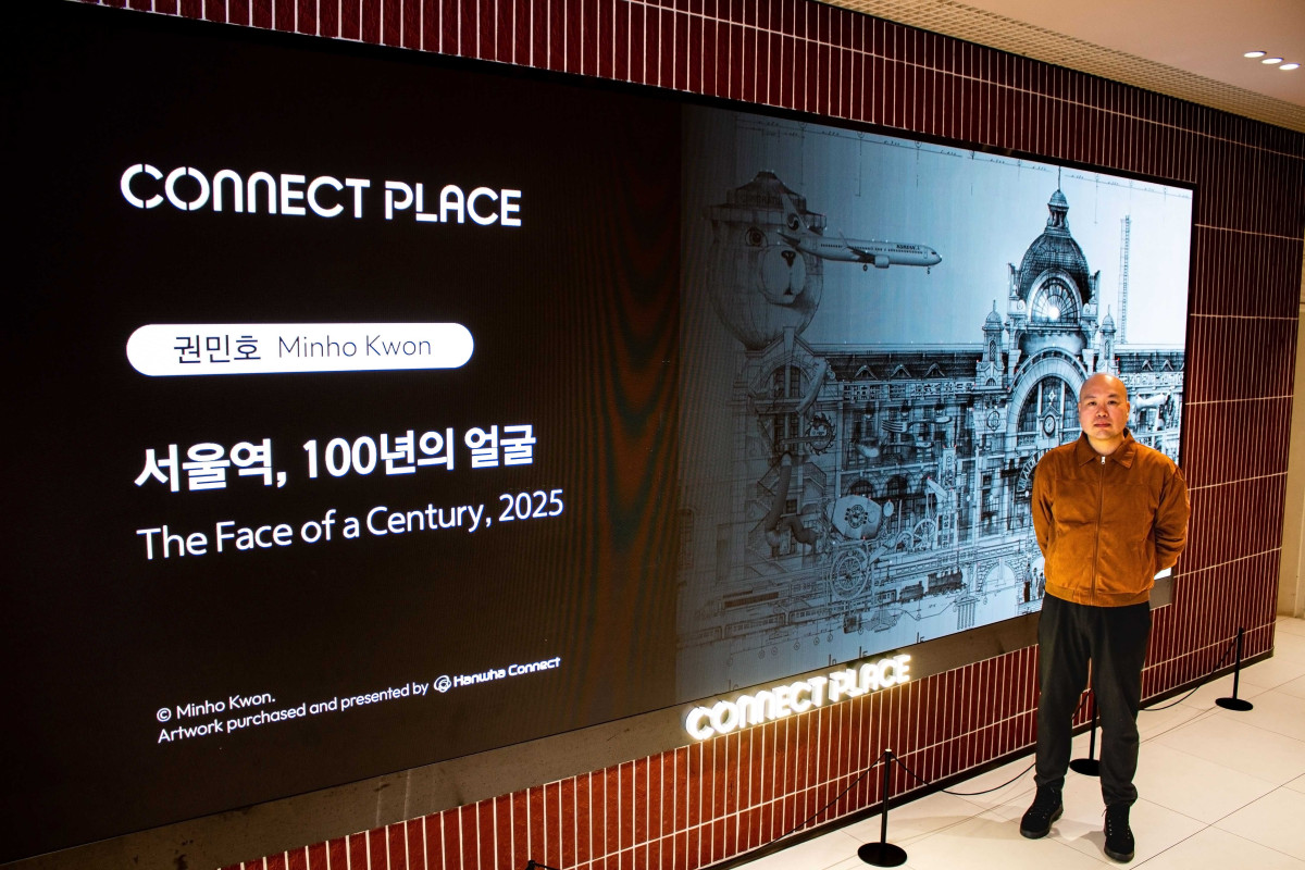 ▲커넥트플레이스 서울역점 ‘서울역, 100년의 얼굴’ 작품 영상 앞에서 사진 촬영 중인 권민호 작가 (사진제공=한화커넥트)