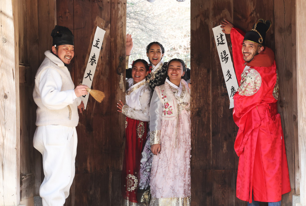 ▲입춘을 이틀 앞둔 2일 경기도 용인시 한국민속촌에서 외국인 관광객들이 어르신과 입춘첩(입춘대길 건양다경)을 붙이고 있다. (연합뉴스)