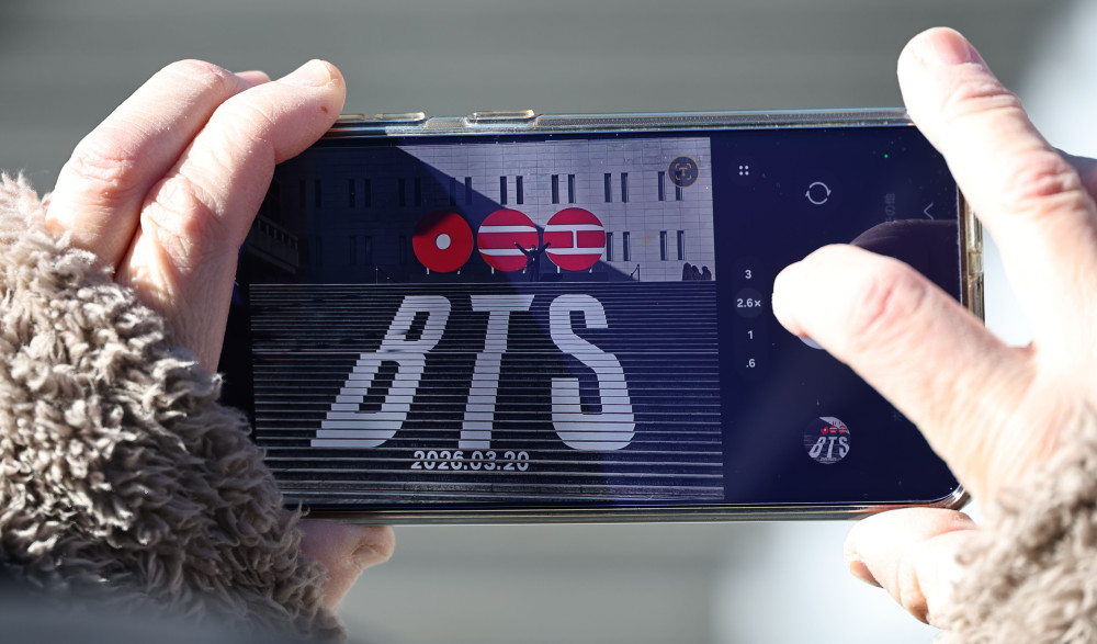 ▲22일 서울 종로구 세종문화회관 계단에서 일본인 관광객들이 오는 3월 3년 9개월 만에 '완전체'로 돌아오는 그룹 방탄소년단(BTS)의 컴백을 알리는 홍보물을 기념촬영하고 있다.  (연합뉴스)