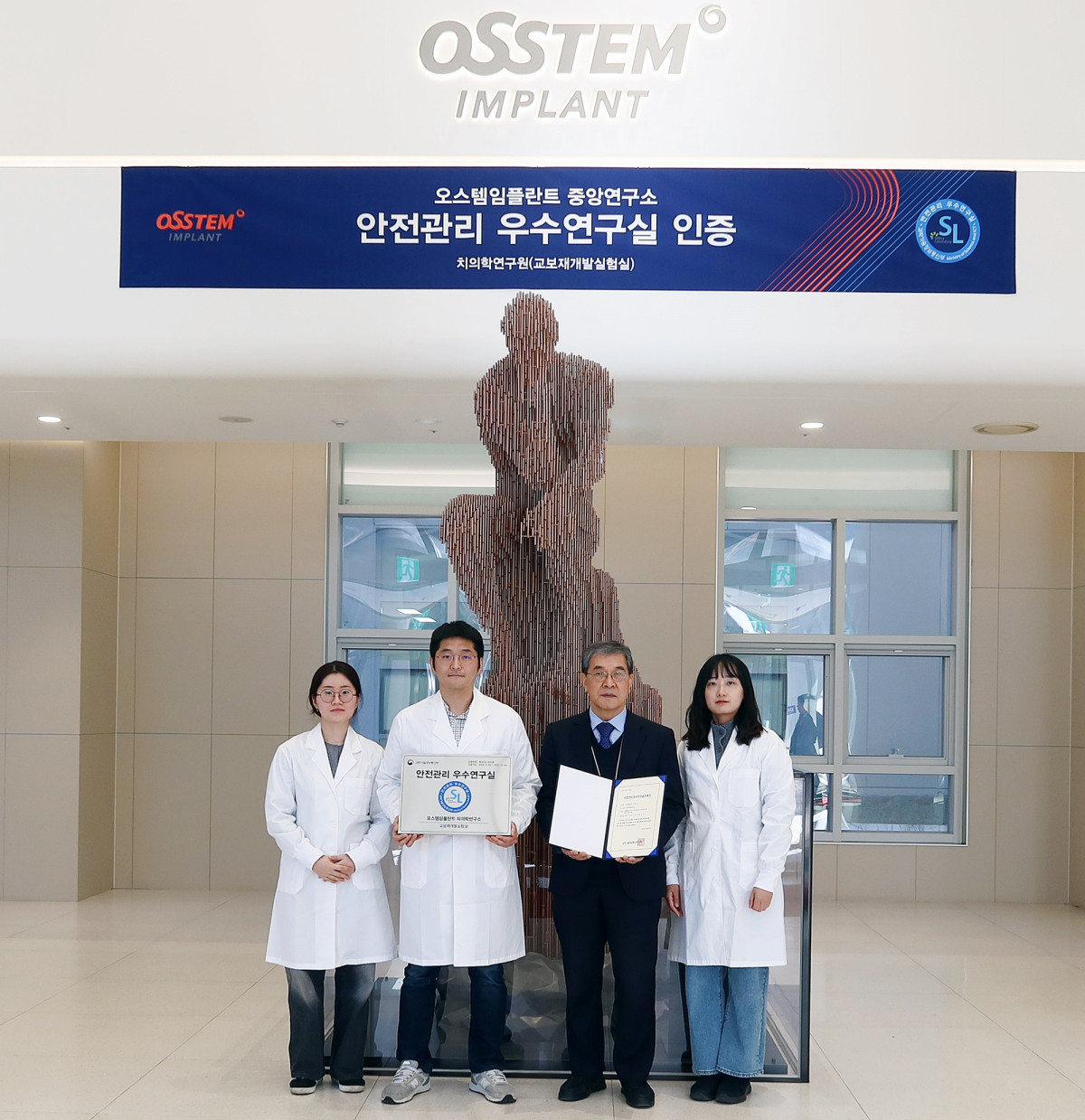 ▲서울 강서구 오스템임플란트 트윈타워 로비에서 조인호 치의학연구원장(왼쪽에서 세번째)을 비롯해 교보재개발실험실 직원들이 과학기술정보통신부의 ‘안전관리 우수연구실’ 인증서 및 명판을 들고 기념촬영을 하고 있다.  (사진제공=오스템임플란트)