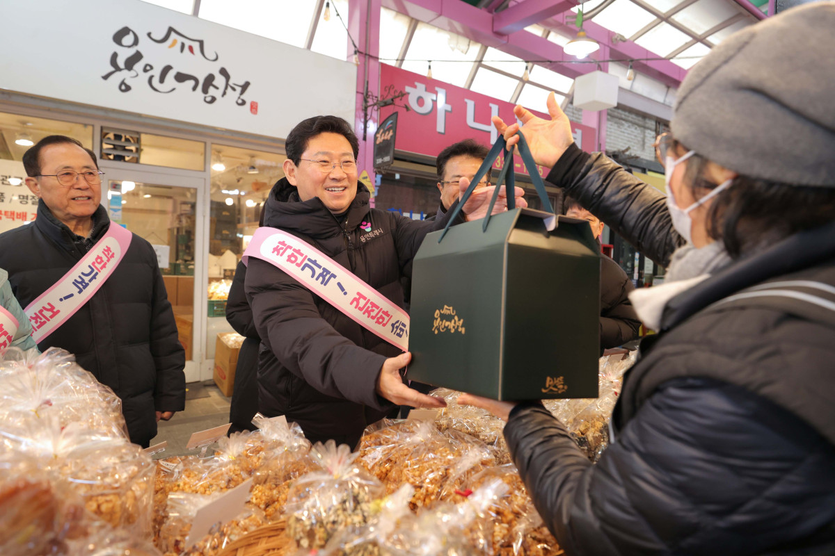 ▲이상일 용인특례시장이 10일 용인중앙시장에서 장을 보며 상인에게 물품을 건네받고 있다. 이 시장은 부인 김미영 여사와 함께 과일, 떡, 전, 빵 등을 구매하며 시민·상인과 명절 인사를 나눴다.  (용인특례시)